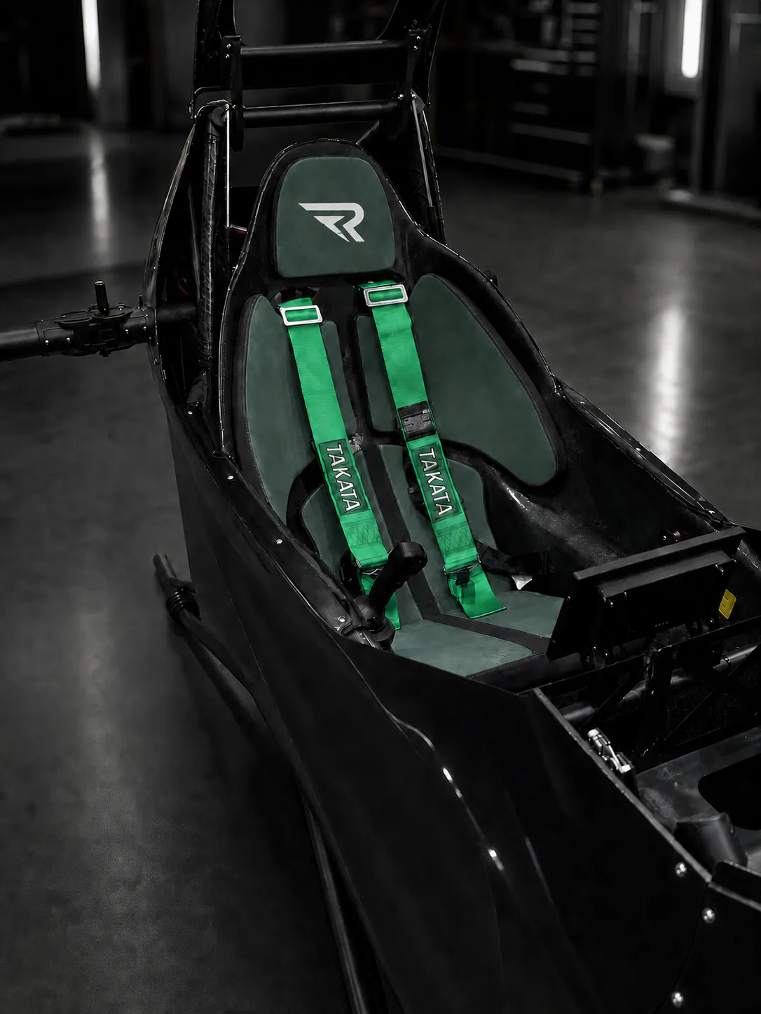 Black REVTOL cockpit with the approved white headrest R and vivid green TAKATA harnesses